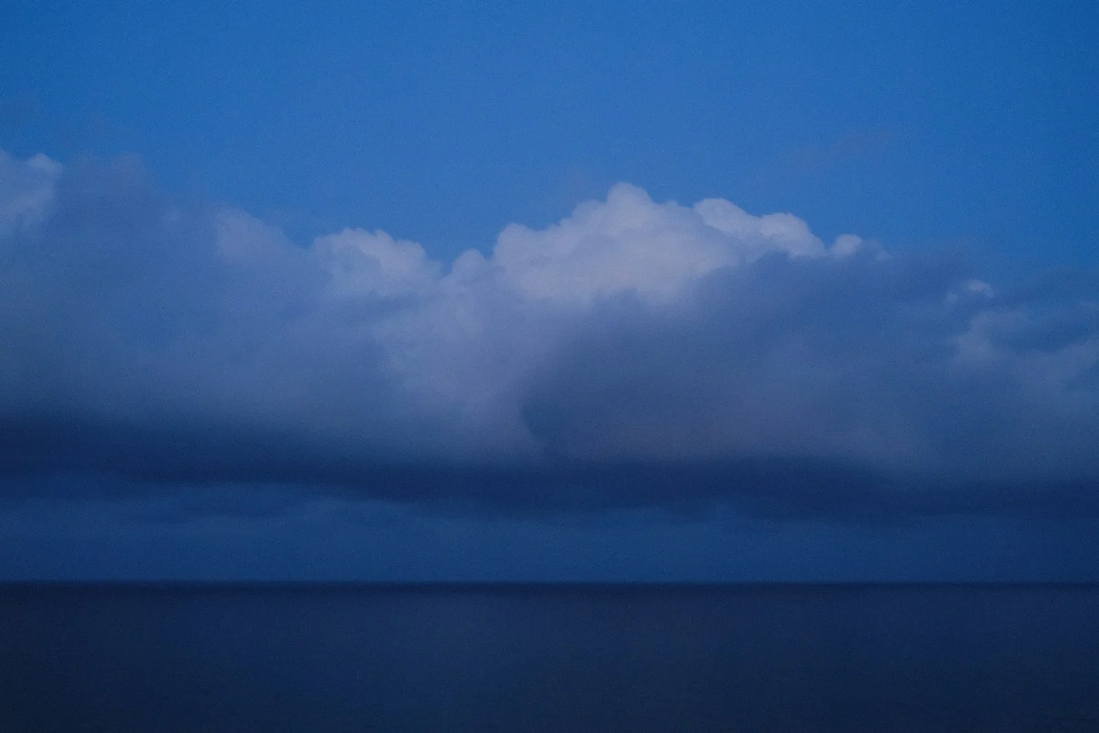 Blue ocean beneath towering clouds